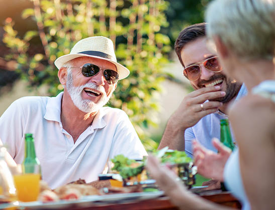 Two generations of family gathered to picnic in the garden on sunny day.